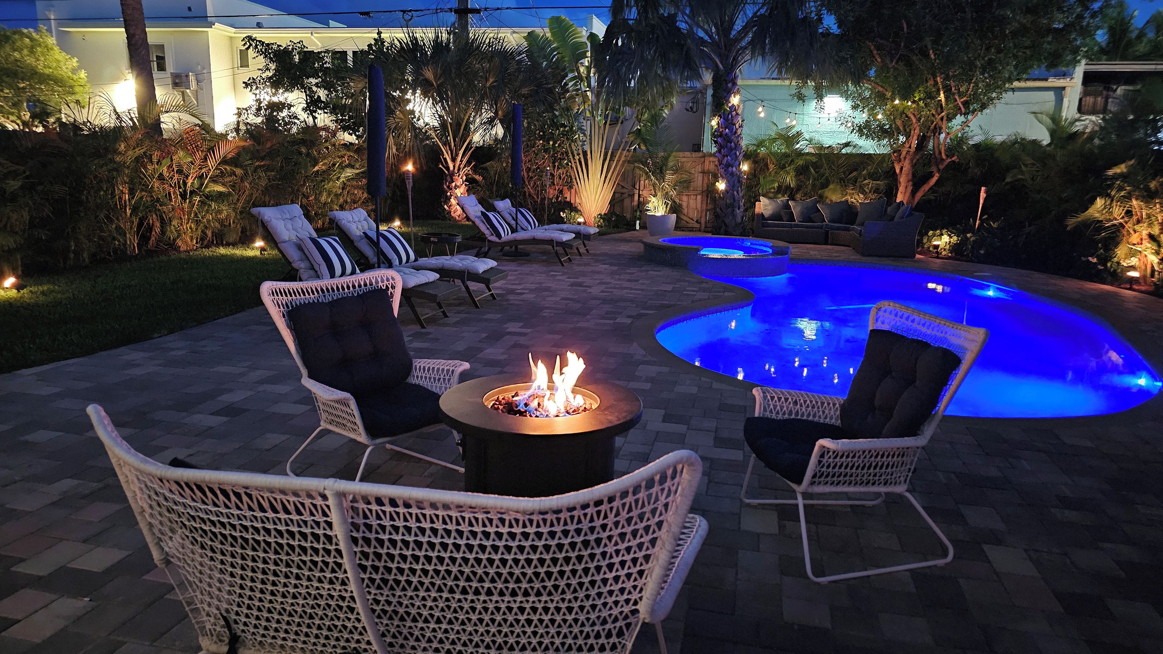 An outdoor patio area with lounge chairs, a fire pit, and a swimming pool.