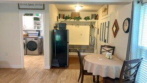 A compact kitchen with a refrigerator, washing machine, and a dining area with a table and chairs.