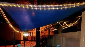 A hot tub with a blue interior, surrounded by a brick wall and a blue canopy.