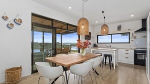 Una cocina moderna con una isla grande, armarios blancos y vistas al exterior.