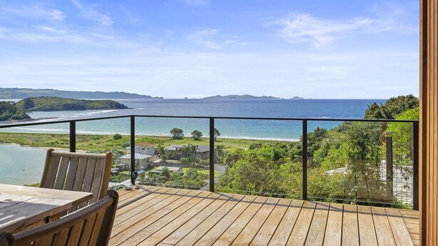 Una terraza de madera con vista al océano y a la costa distante.