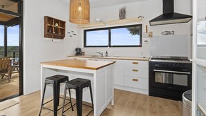 Una cocina moderna con una isla grande, electrodomésticos negros y vistas al exterior.