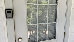 A white door with a window, a doorbell, and a keyhole.