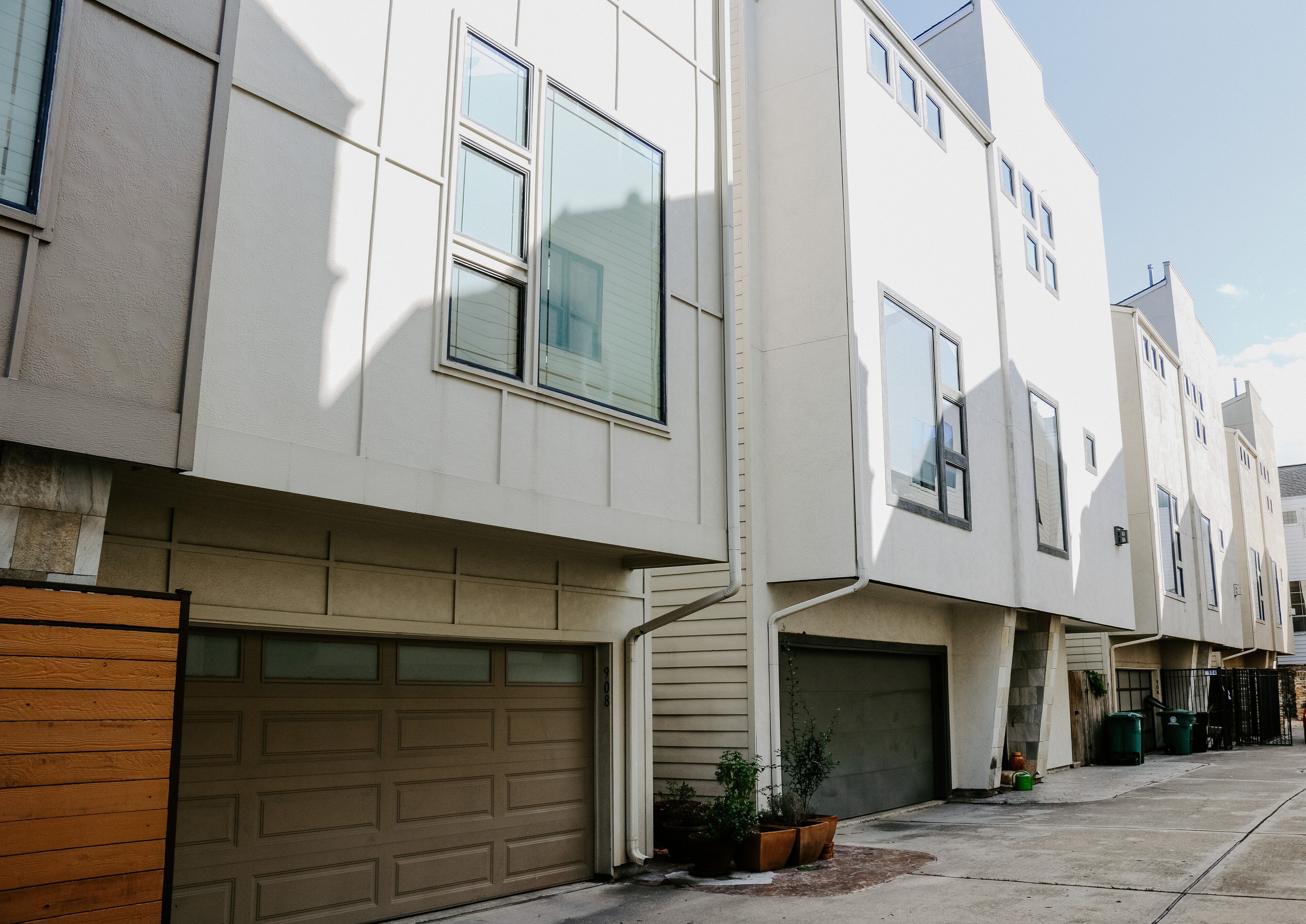 A row of modern townhouses with garage doors, large windows, and a clean, white facade.