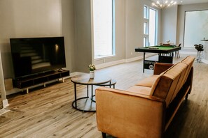 A modern living room with a flat-screen TV, a pool table, and a sofa.