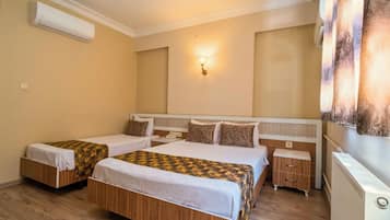 Habitación de hotel con dos camas, una mesita de noche, una lámpara y un aire acondicionado instalado en la pared.