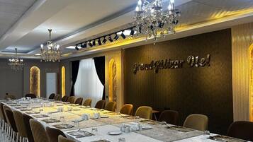 A conference room with a long table, chairs, chandeliers, and a wall with a sign.