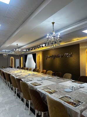 A conference room with a long table, chairs, chandeliers, and a wall with a sign.