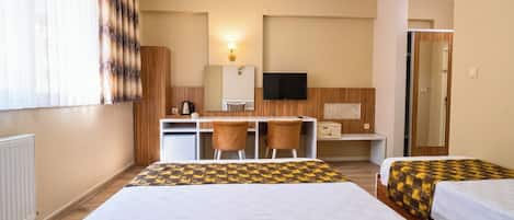A hotel room with two beds, a desk, and a television.