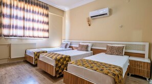 A hotel room with two single beds, a radiator, an air conditioning unit, and a window with curtains. - Grand Gulizar Hotel (Sanliurfa)