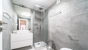 Un baño moderno con ducha de vidrio, inodoro blanco y tocador con espejo.