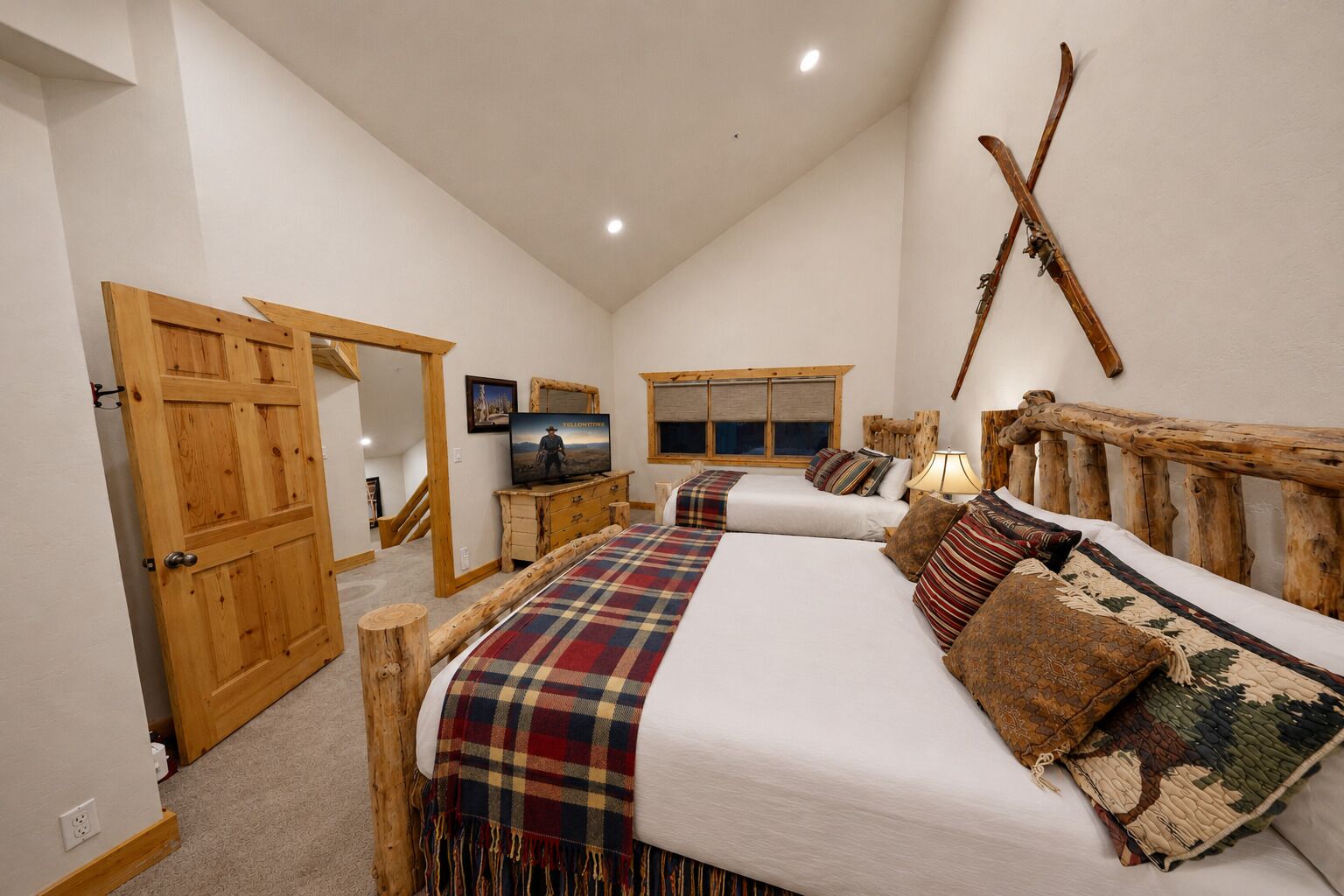 Une chambre avec deux lits, des têtes de lit en bois, une télévision et une fenêtre.