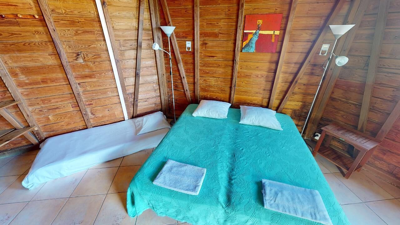 A room with a bed, two bedside tables, a floor lamp, and a painting on the wall.
