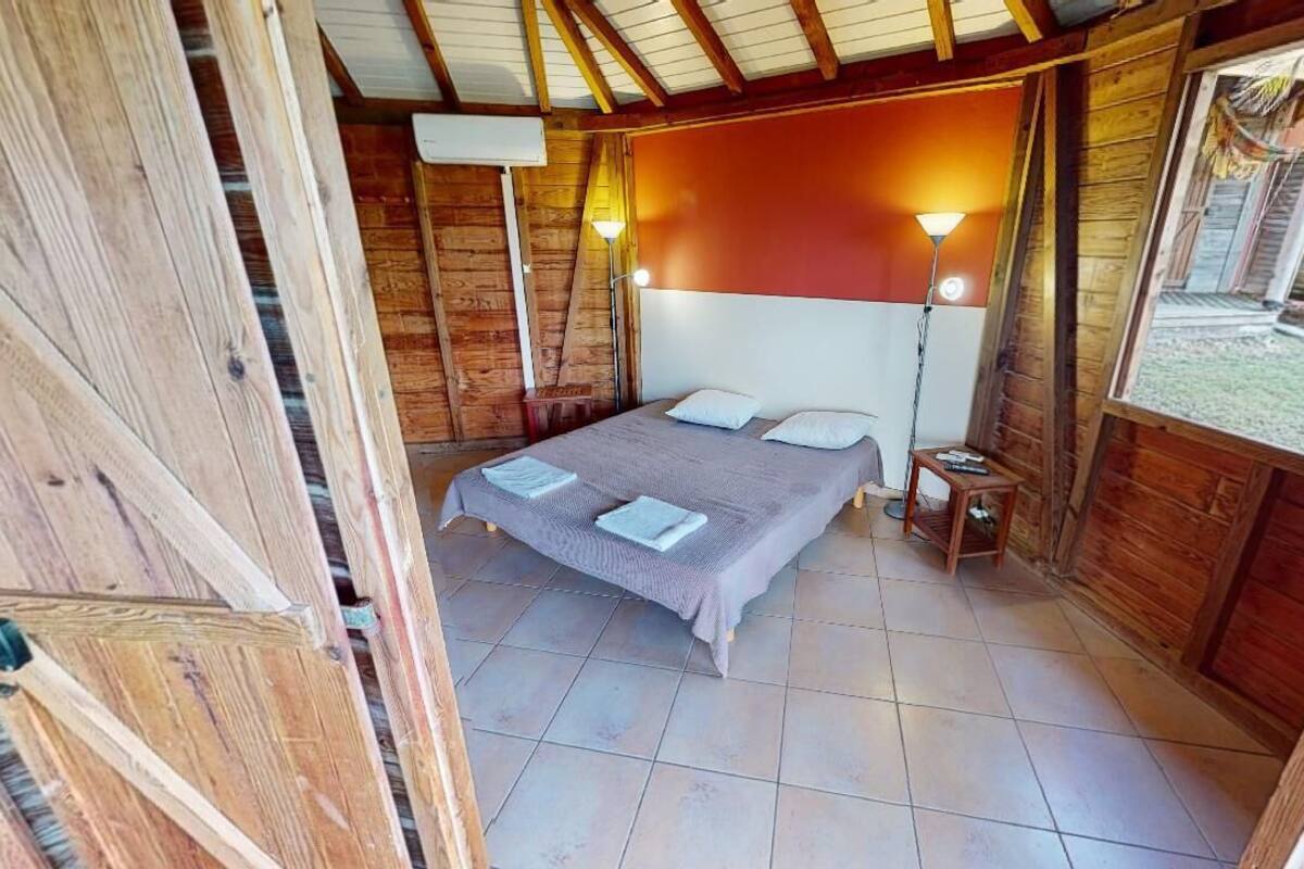Una habitación de madera con una cama, dos lámparas de noche y vistas al exterior.