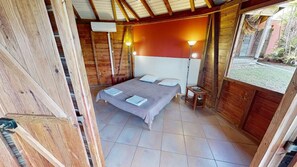 A wooden room with a bed, two bedside lamps, and a view of the outside.