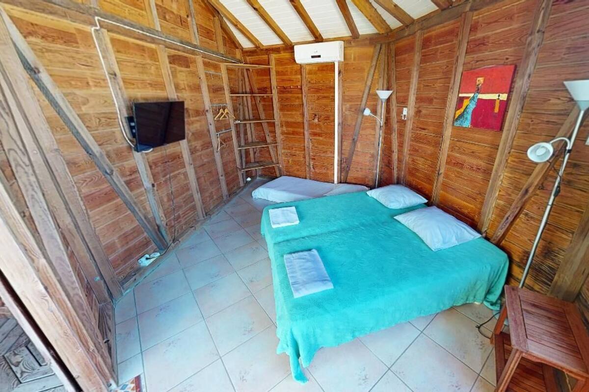 Una habitación pequeña y acogedora con una cama individual, un televisor en la pared y una escalera.