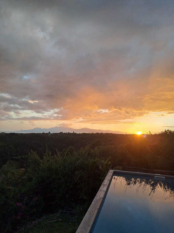 Vista al atardecer sobre un paisaje con piscina en primer plano.