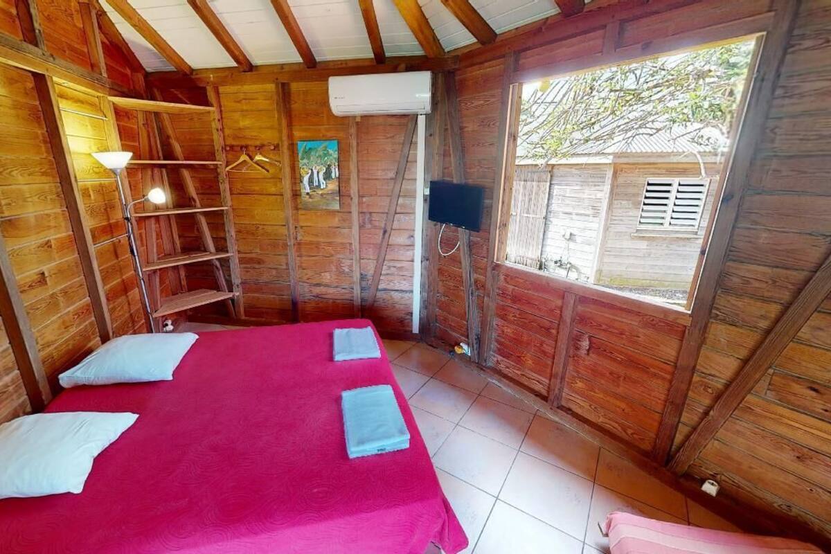 Una habitación tipo cabaña de madera con una cama, una escalera, un televisor y una ventana.