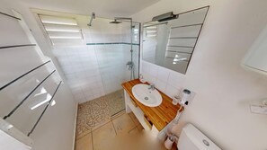 A bathroom with a shower, a sink, and a mirror.