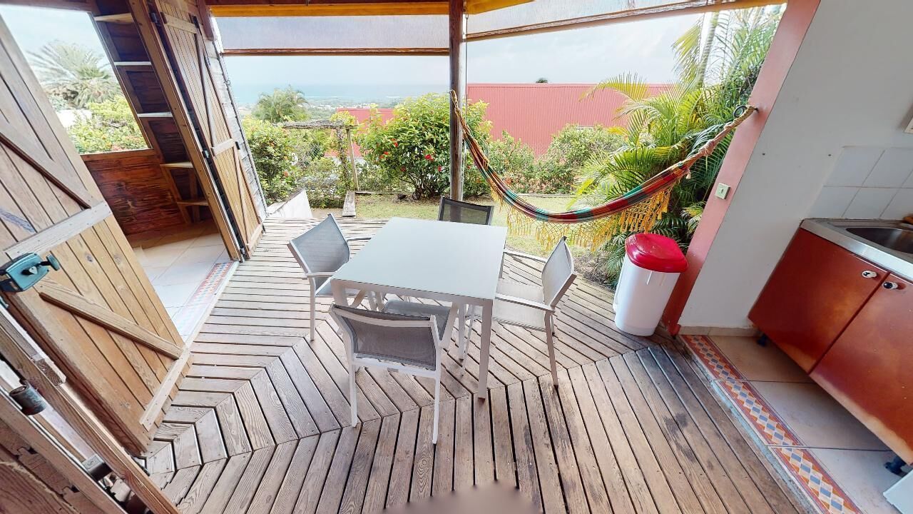 Een houten terras met een visgraatvloer, een witte tafel met stoelen en een hangmat.