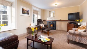 Una sala de estar acogedora con chimenea, muebles de cuero y un televisor.