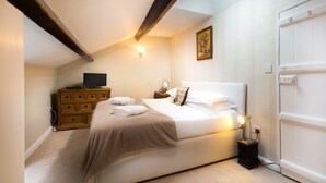 Un dormitorio con cama, cómoda de madera, televisor y puerta.