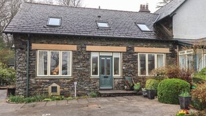 A stone house with a green door, two windows with white frames, and a small porch area. - Middlerigg (Windermere)