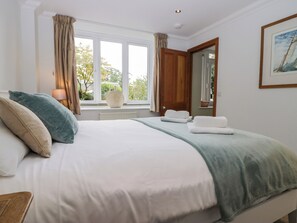 A hotel room with a large bed, a window with curtains, a bedside lamp, and a framed picture on the wall. - Middlerigg (Windermere)