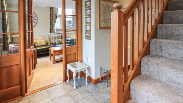 A spacious living area with a staircase, a small table, and a sofa. - Middlerigg (Windermere)