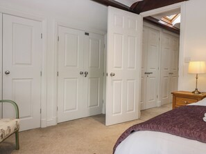 Une chambre à coucher avec un lit, une table de chevet avec une lampe, une chaise et une armoire sur laquelle est apposée une pancarte indiquant « PRIVÉ ».