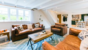 Ein geräumiges Wohnzimmer mit Ledersofas, einem Holztisch und einem großen Fenster.