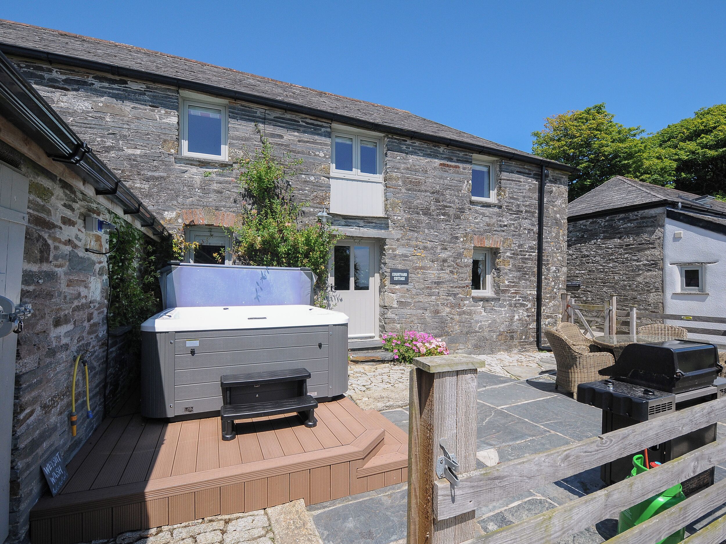 A stone building with a hot tub and outdoor seating area.