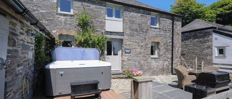 A stone building with a hot tub and outdoor seating area.