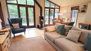 A cozy living room with a fireplace, a sofa, a chair, and a dining area with a table and chairs. - Beck of Beyond (Ambleside)