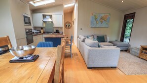 A modern kitchen with a dining area, a sofa, and a map on the wall. - Beck of Beyond (Ambleside)