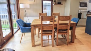 A dining area with a wooden table and chairs, a lamp, and a view of the outside. - Beck of Beyond (Ambleside)