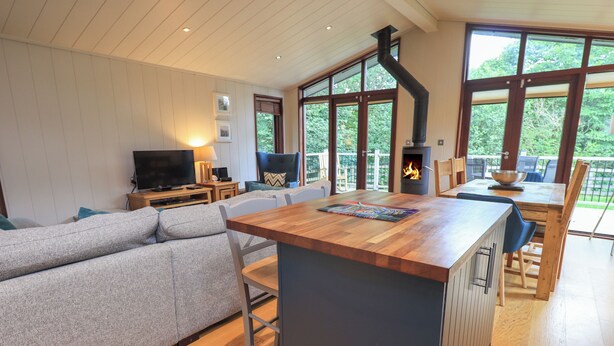 A modern living room with a wooden island, grey sofa, and a TV on a wooden stand. - Beck of Beyond (Ambleside)