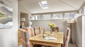 A dining area with a wooden table, plaid upholstered chairs, a vase with sunflowers, and a bottle of wine. - Archie's (Ambleside)