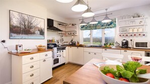 A modern kitchen with white cabinetry, a wooden countertop, and a large window with a view. - Juniper Cottage (Windermere)
