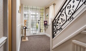 A hallway with a staircase, a door with glass panels, and a small table with a sculpture. - Heathfield (Keswick)