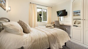 Une chambre à coucher comprenant un lit, un bureau, une chaise, un téléviseur et une armoire.