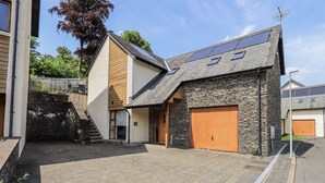 A modern house with a stone facade, a wooden door, and a paved driveway.