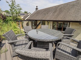 An outdoor patio with a round table and wicker chairs, surrounded by glass railings.