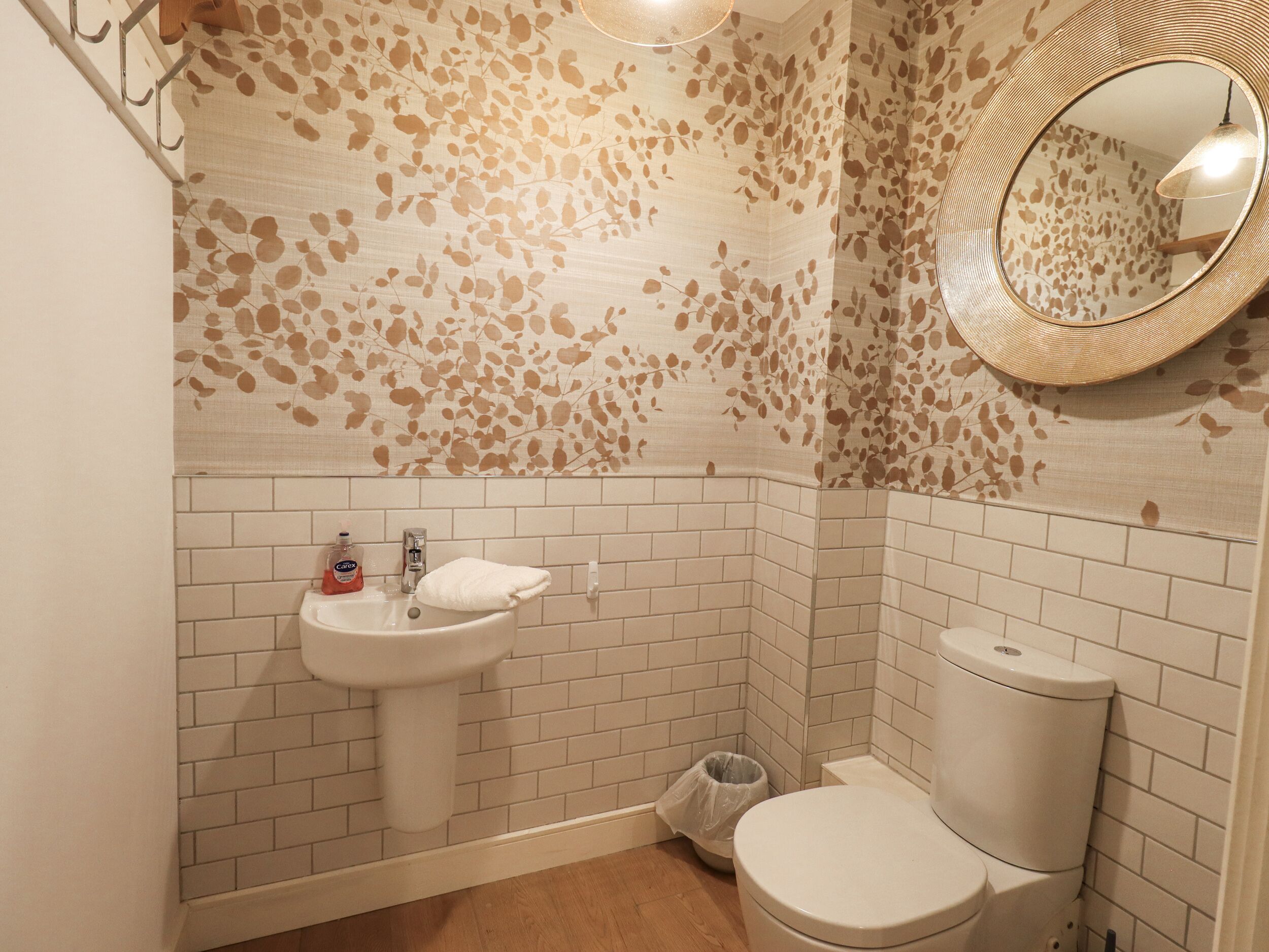 A bathroom with a white sink, toilet, and a mirror with a circular frame.