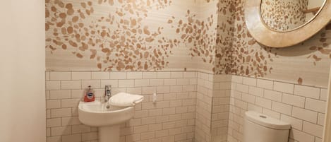 A bathroom with a white sink, toilet, and a mirror with a circular frame.