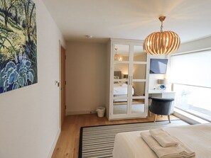 A modern bedroom with a bed, a large window, a hanging light fixture, and a painting on the wall. - No 7 (Ambleside)