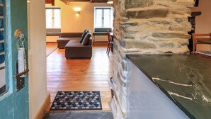 A cozy interior with a stone wall, wooden flooring, a sofa, and a bench.