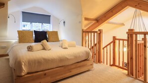 A bedroom with a large bed, wooden headboard, and a view of the outdoors through a window.