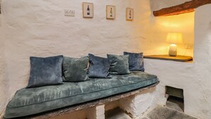 Un banco de piedra con cojines, una lámpara fijada a la pared y cuadros enmarcados.