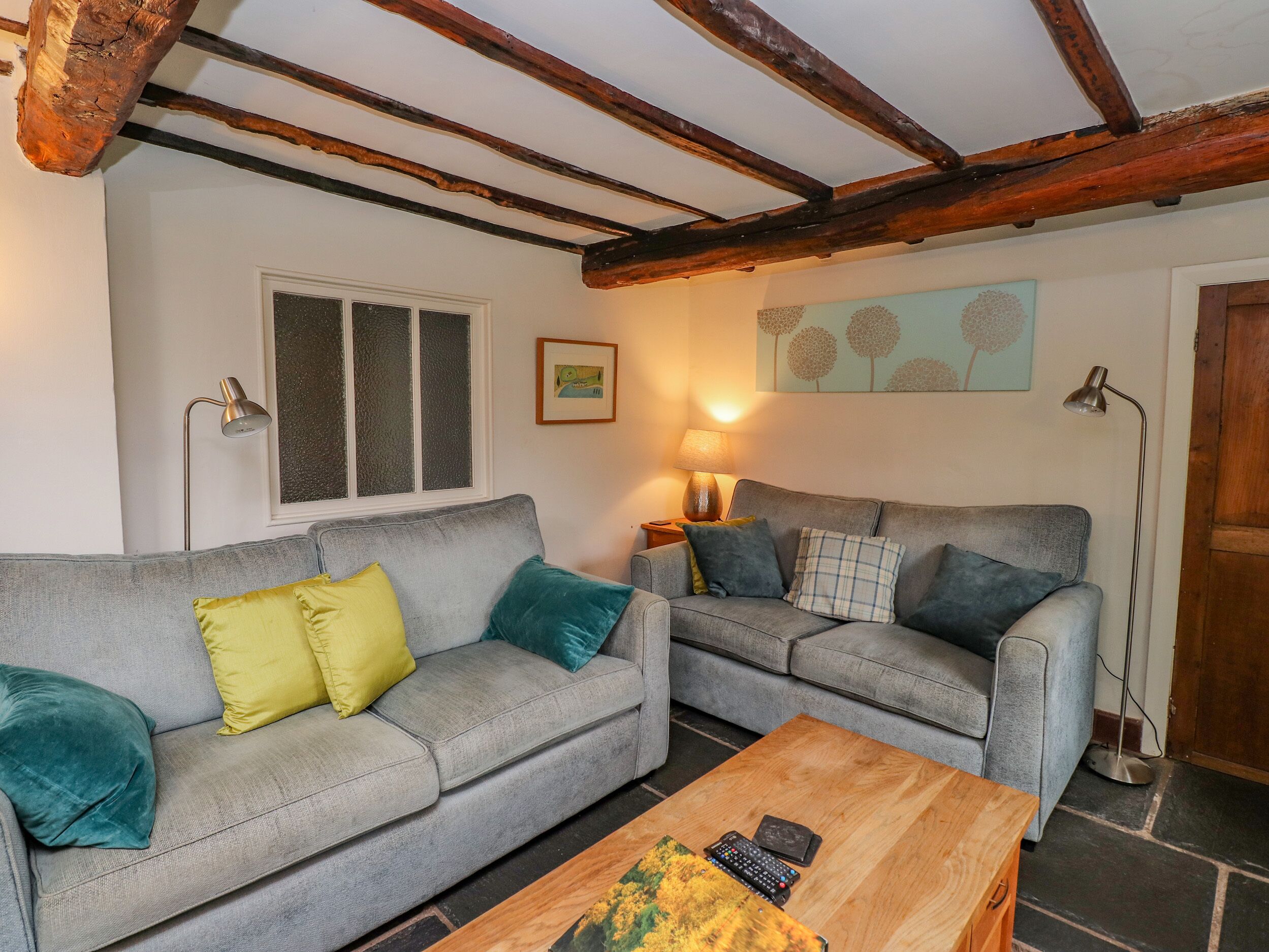 Ein Wohnzimmer mit zwei grauen Sofas, einem Holztisch und einer Lampe.